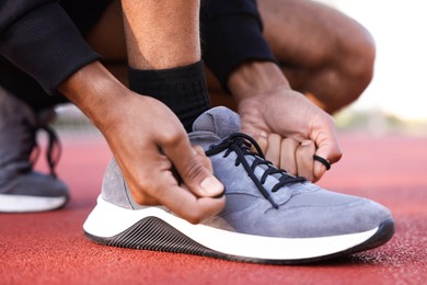 Photo of Runner tying shoelace of his sneaker at stadium, closeup