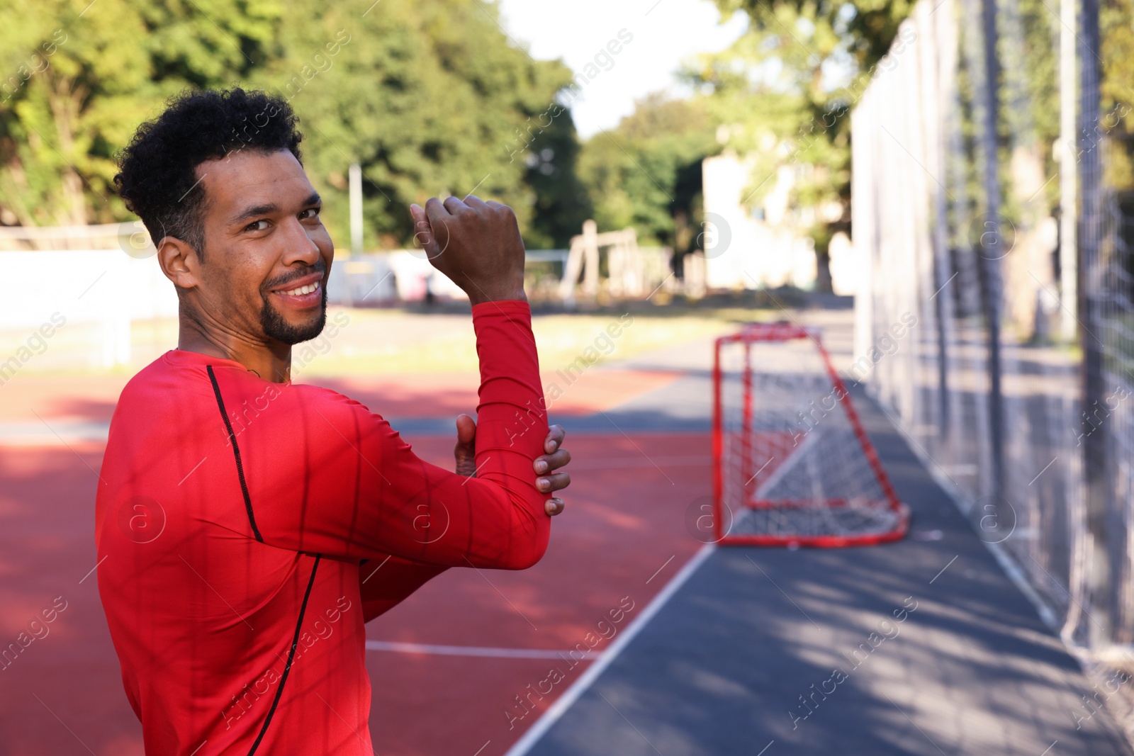 Smiling man in sportswear doing warm-up exercise before run at stadium. Space for text Photo of Smiling man in sportswear doing warm-up exercise before run at stadium. Space for text
