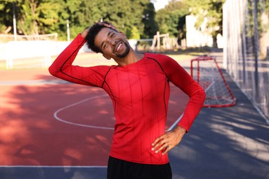 Photo of Smiling man in sportswear doing warm-up exercise before run at stadium