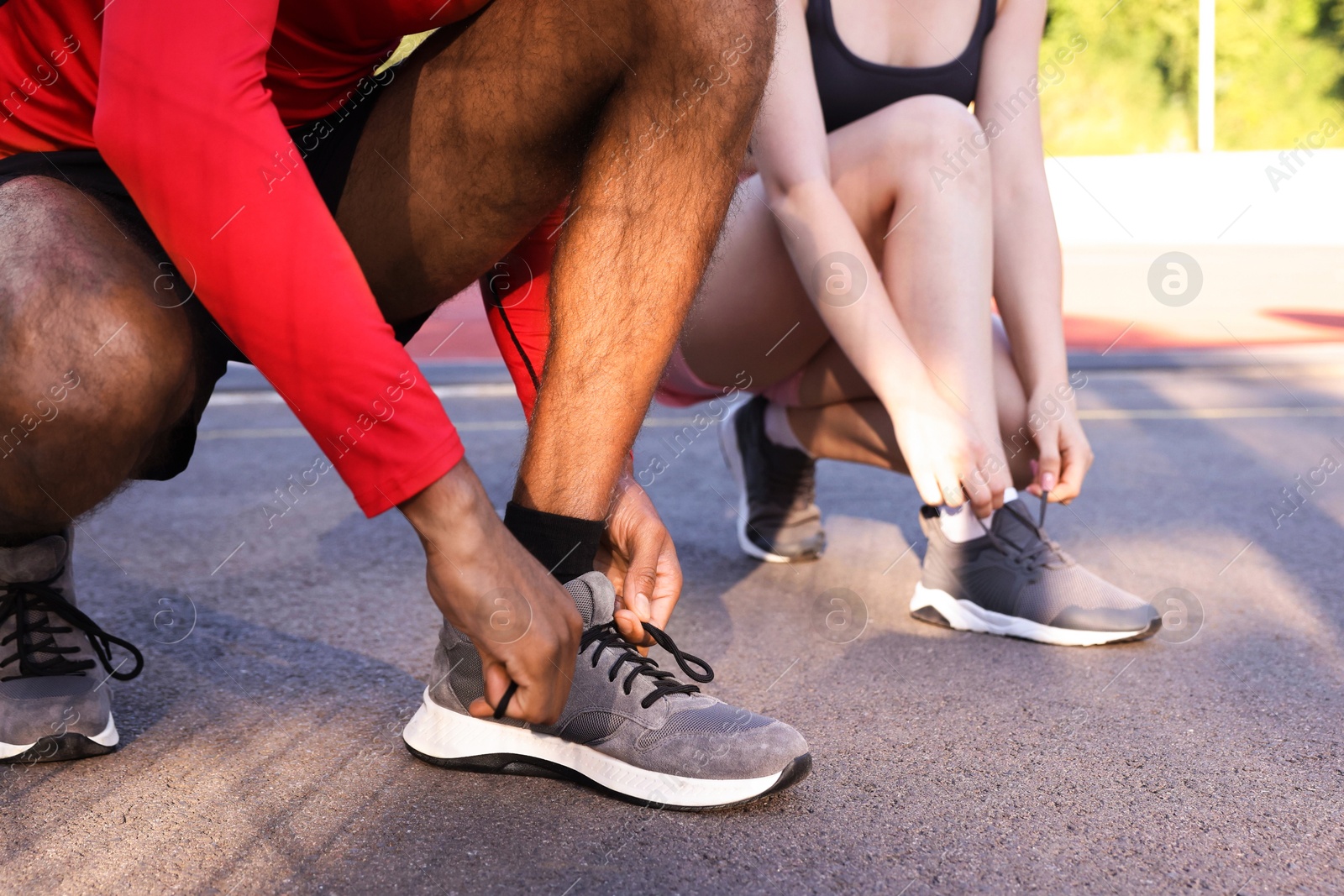 Runners tying shoelaces of their sneakers at stadium, closeup Photo of Runners tying shoelaces of their sneakers at stadium, closeup