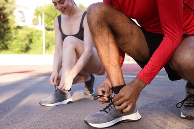 Photo of Runners tying shoelaces of their sneakers at stadium, closeup