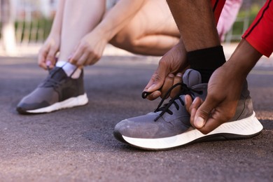 Photo of Runners tying shoelaces of their sneakers at stadium, closeup