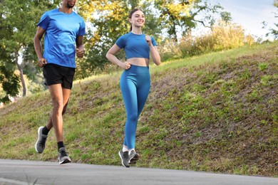 Photo of Couple in sportswear running in park, closeup. Space for text