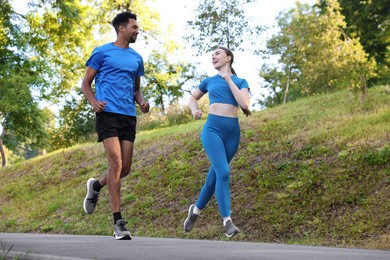 Photo of Couple in sportswear running in park, low angle view