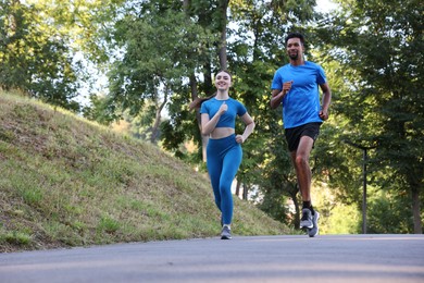Photo of Couple in sportswear running in park, low angle view. Space for text