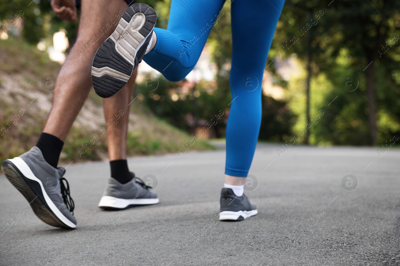Photo of Couple in sneakers running in park, closeup. Space for text