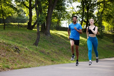 Photo of Couple in sportswear running in park. Space for text