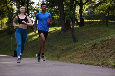 Photo of Couple in sportswear running in park, low angle view. Space for text