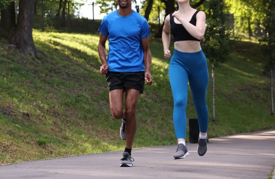 Photo of Couple in sportswear running in park, closeup. Space for text