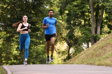 Photo of Couple in sportswear running in park, low angle view. Space for text