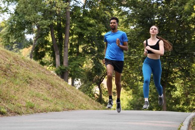 Photo of Couple in sportswear running in park, low angle view. Space for text