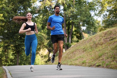 Photo of Couple in sportswear running in park, low angle view. Space for text