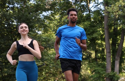 Photo of Couple in sportswear running in park, low angle view