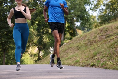 Photo of Couple in sportswear running in park, closeup. Space for text