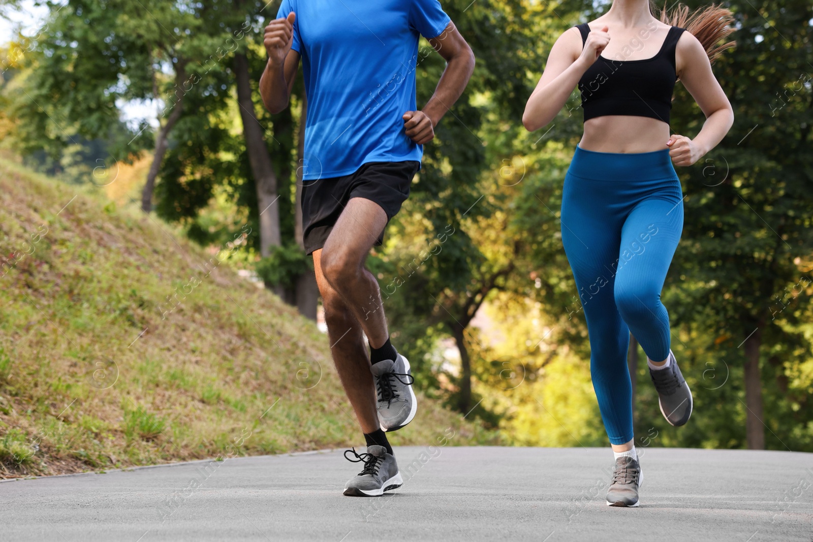 Couple in sportswear running in park, closeup. Space for text Photo of Couple in sportswear running in park, closeup. Space for text