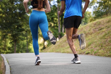 Photo of Couple in sportswear running in park, closeup