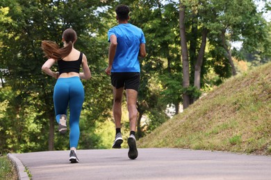 Photo of Couple in sportswear running in park, back view. Space for text