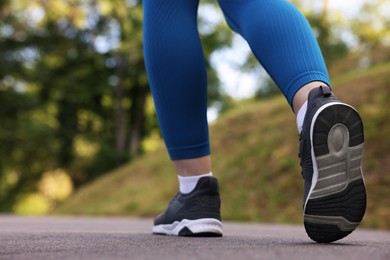 Photo of Woman in sneakers running in park, closeup. Space for text