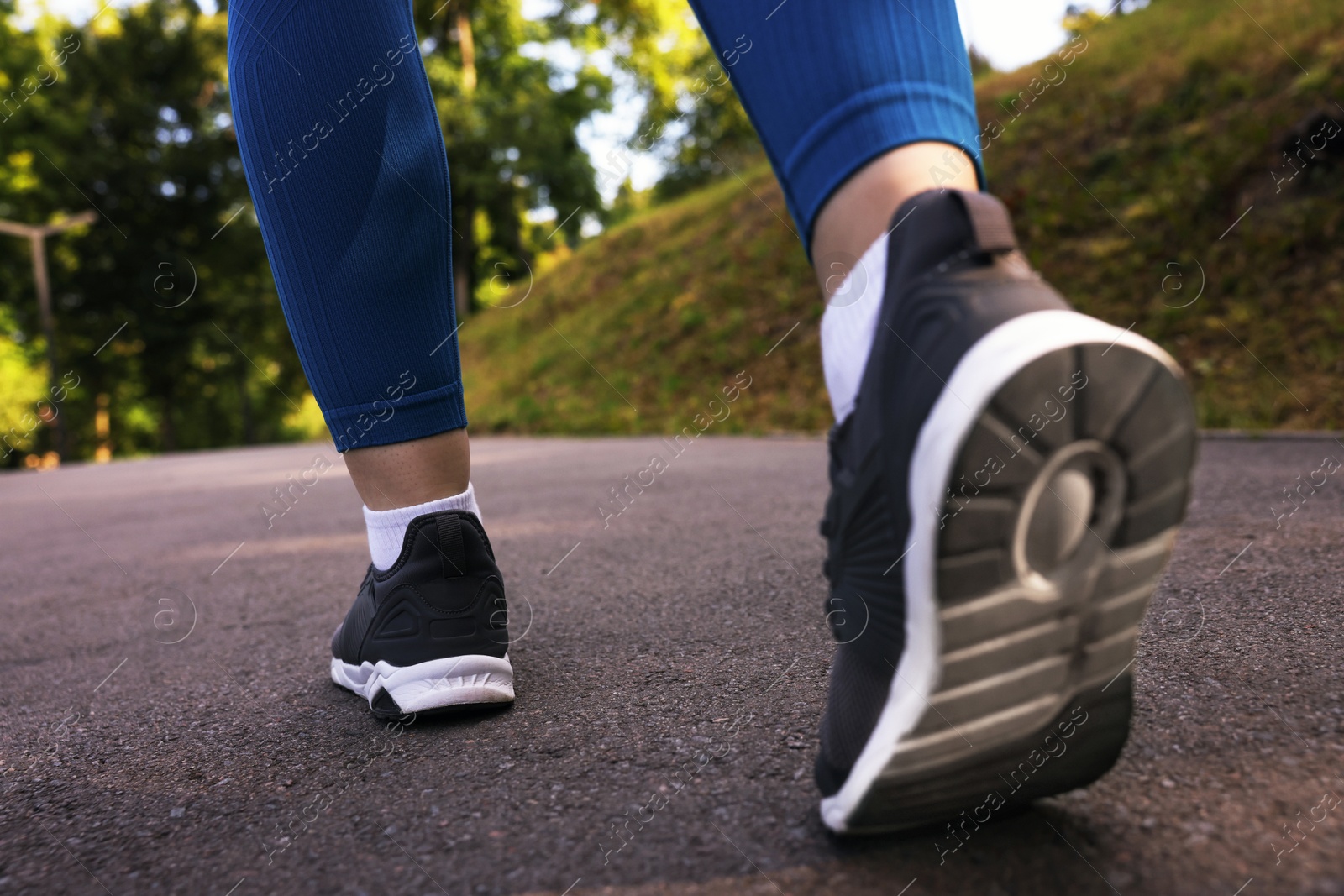 Woman in sneakers running in park, closeup Photo of Woman in sneakers running in park, closeup