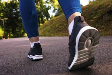 Photo of Woman in sneakers running in park, closeup