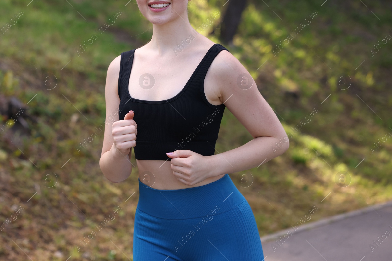 Smiling woman in sportswear running in park, closeup Photo of Smiling woman in sportswear running in park, closeup