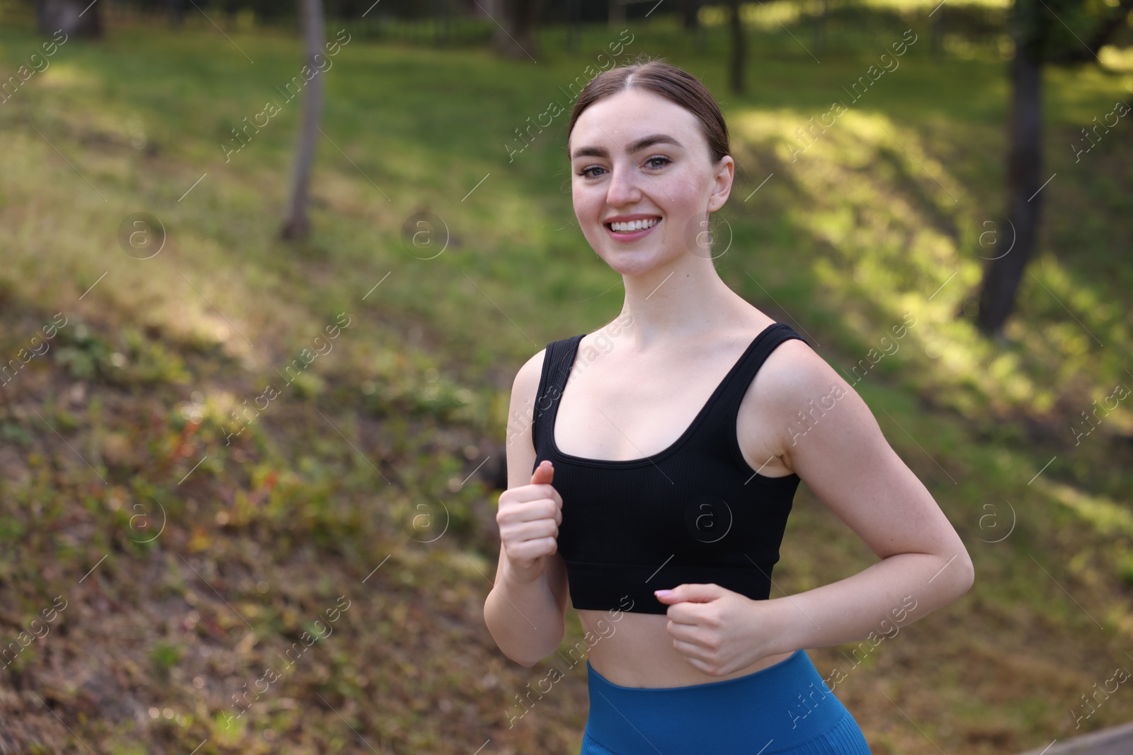 Smiling woman in sportswear running in park. Space for text Photo of Smiling woman in sportswear running in park. Space for text