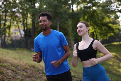Photo of Smiling couple in sportswear running in park