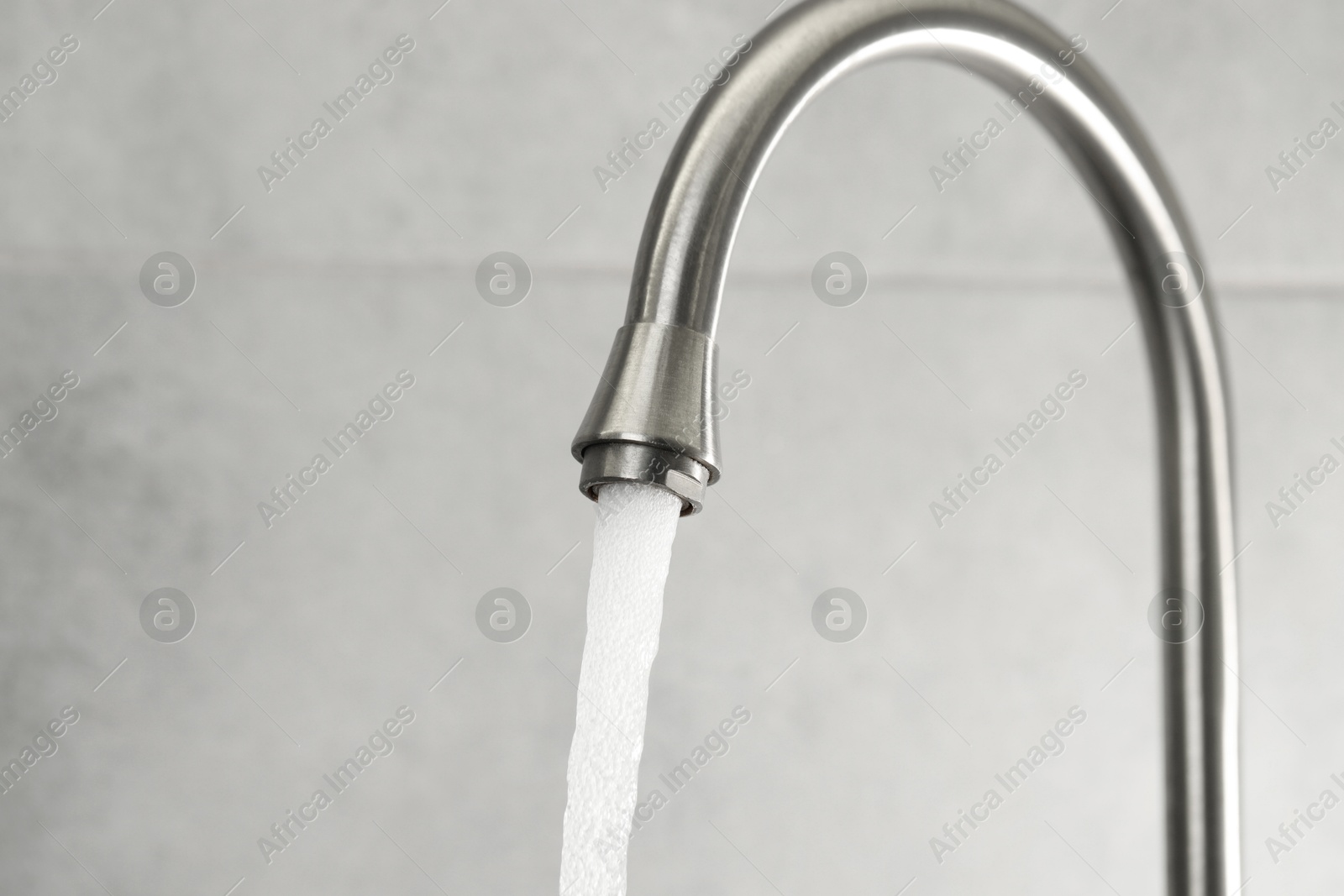 Photo of Water saving concept. Stream of water flowing from tap indoors, closeup