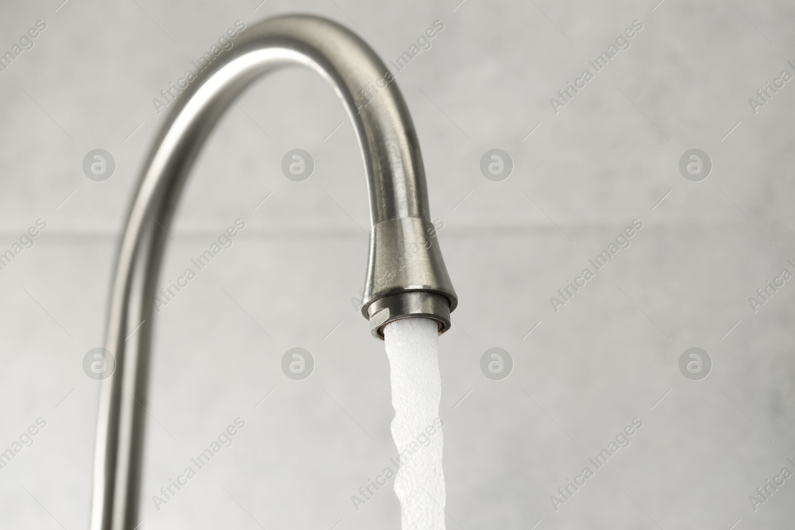 Photo of Water saving concept. Stream of water flowing from tap indoors, closeup