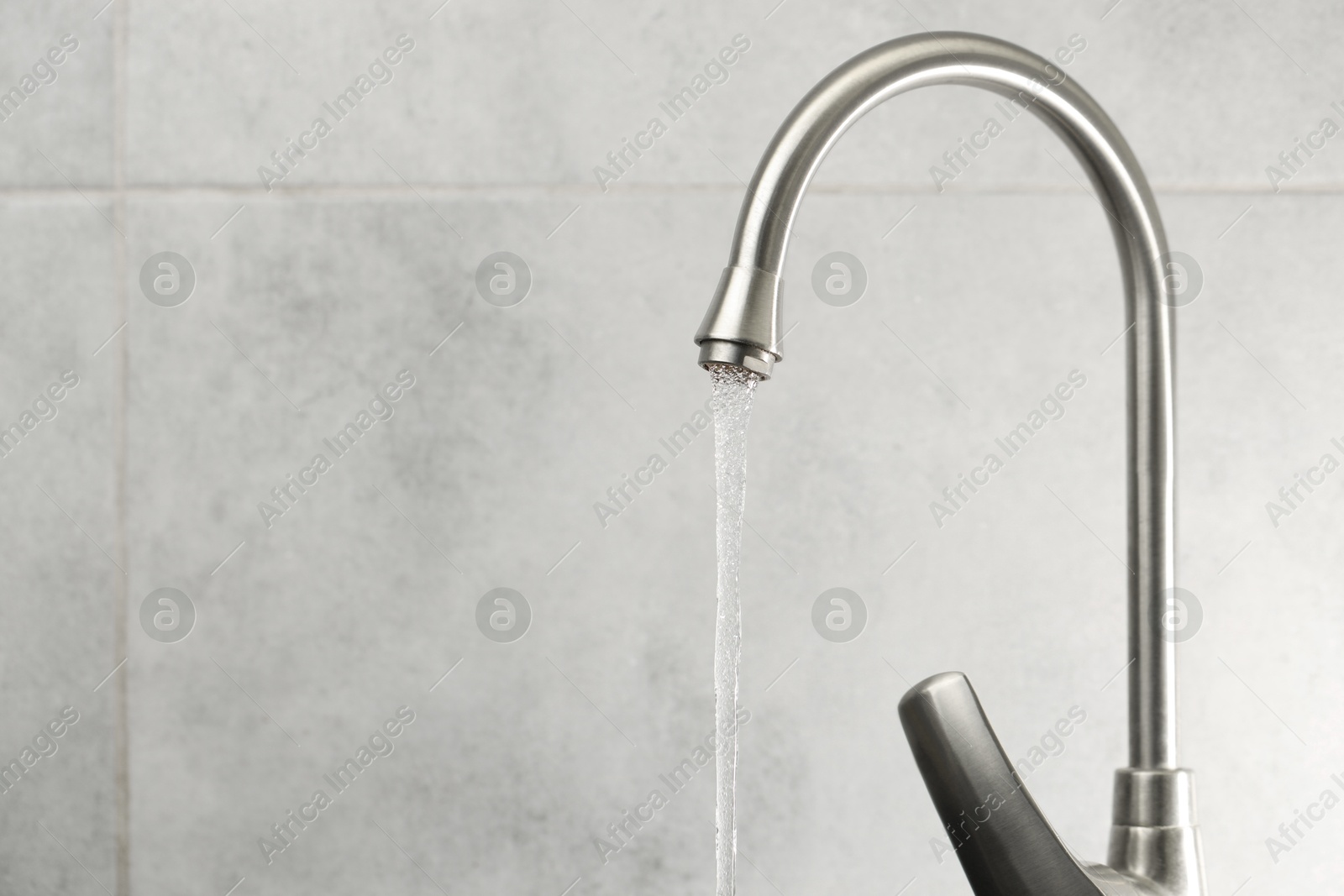 Photo of Water saving concept. Stream of water flowing from tap indoors, closeup. Space for text