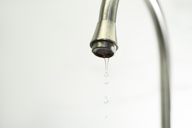 Photo of Save water concept. Water dripping from tap on light background, closeup. Space for text