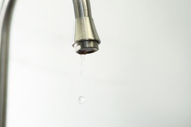 Photo of Save water concept. Water dripping from tap on light background, closeup. Space for text