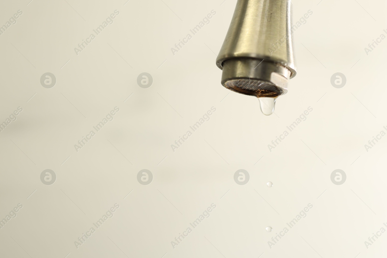 Photo of Save water concept. Water dripping from tap on light background, closeup. Space for text
