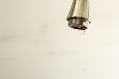 Photo of Save water concept. Water dripping from tap on light background, closeup. Space for text