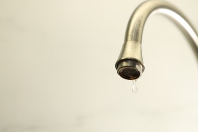 Photo of Save water concept. Water dripping from tap on light background, closeup. Space for text