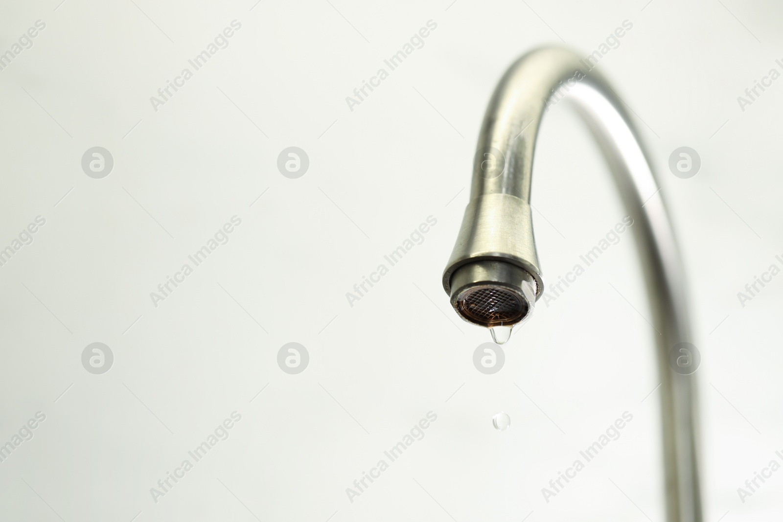 Photo of Save water concept. Water dripping from tap on light background, closeup. Space for text
