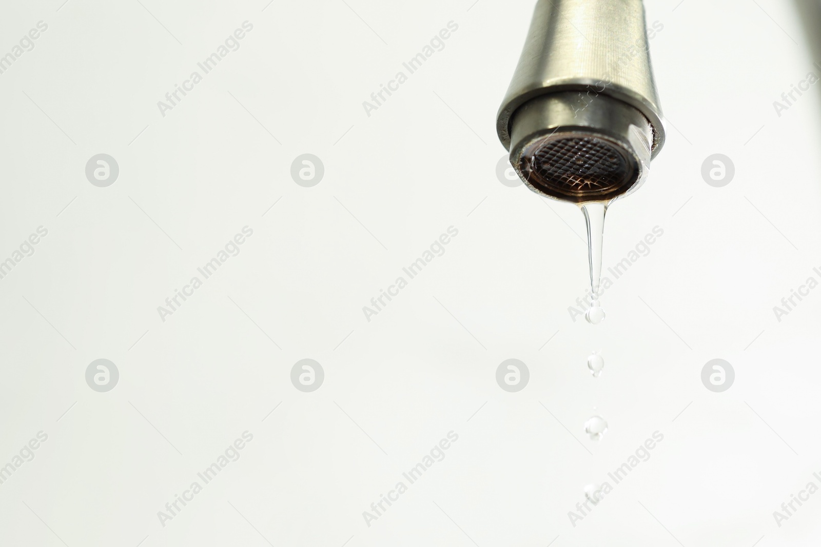 Photo of Save water concept. Water dripping from tap on light background, closeup. Space for text