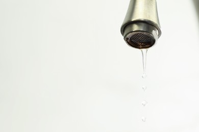 Photo of Save water concept. Water dripping from tap on light background, closeup. Space for text