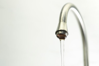Photo of Save water concept. Stream of water flowing from tap on light background, closeup. Space for text