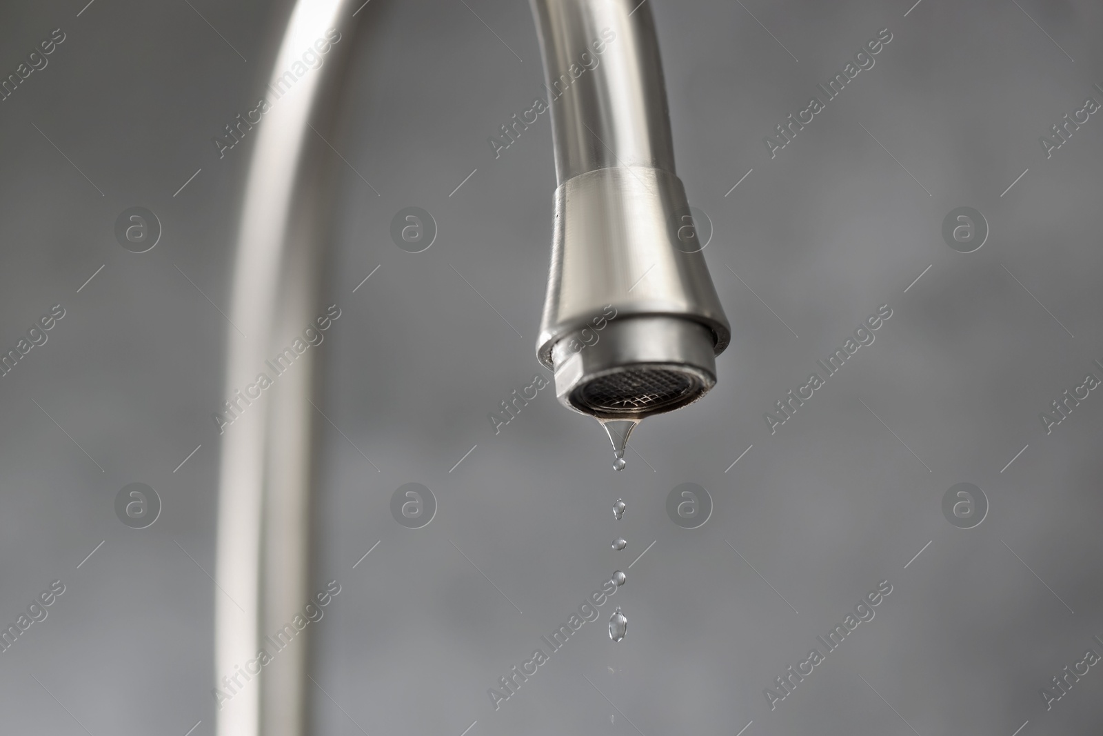 Photo of Save water concept. Water dripping from tap on grey background, closeup