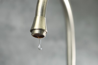 Photo of Save water concept. Water dripping from tap on grey background, closeup