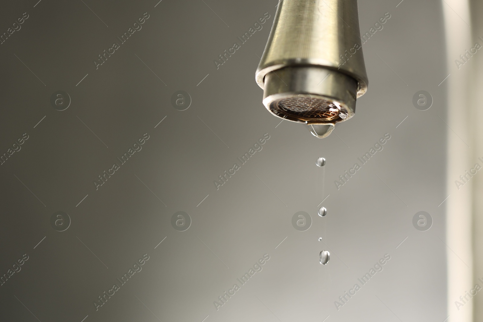 Photo of Water saving concept. Water dripping from tap on grey background, closeup. Space for text
