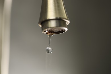 Photo of Save water concept. Water dripping from tap on grey background, closeup