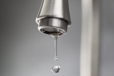 Photo of Save water concept. Water dripping from tap on grey background, closeup