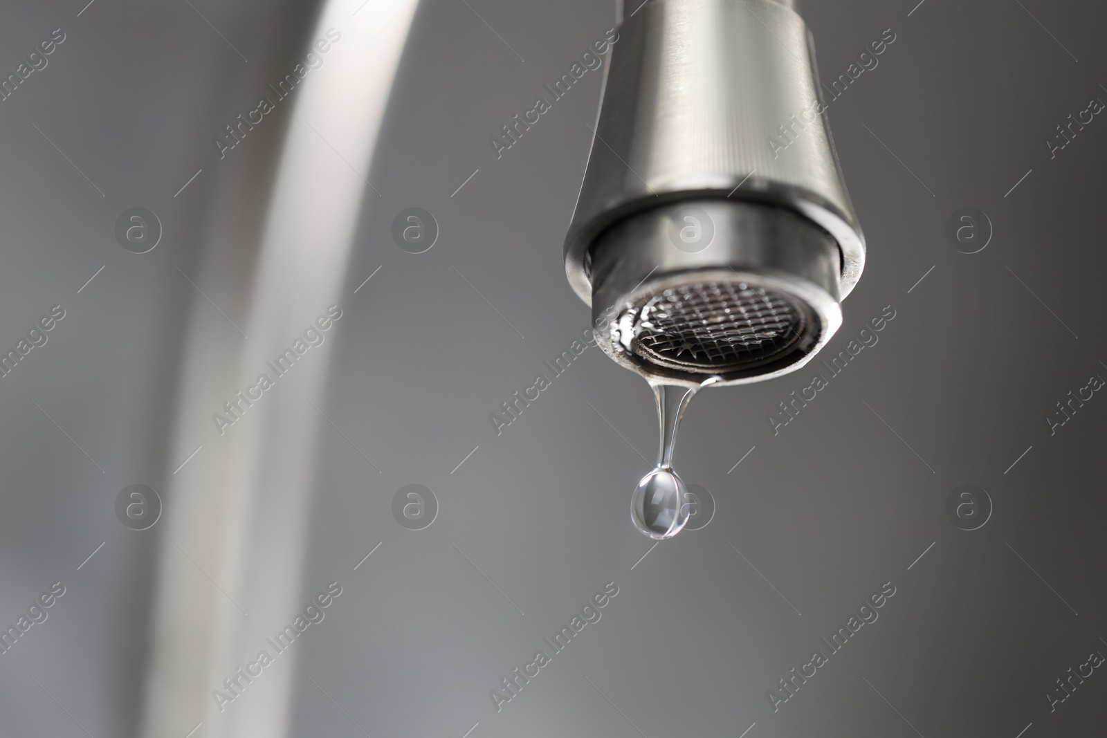 Photo of Save water concept. Water dripping from tap on grey background, closeup. Space for text