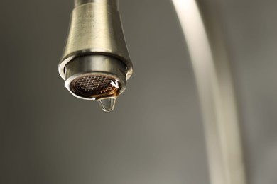 Photo of Save water concept. Water dripping from tap on grey background, closeup. Space for text