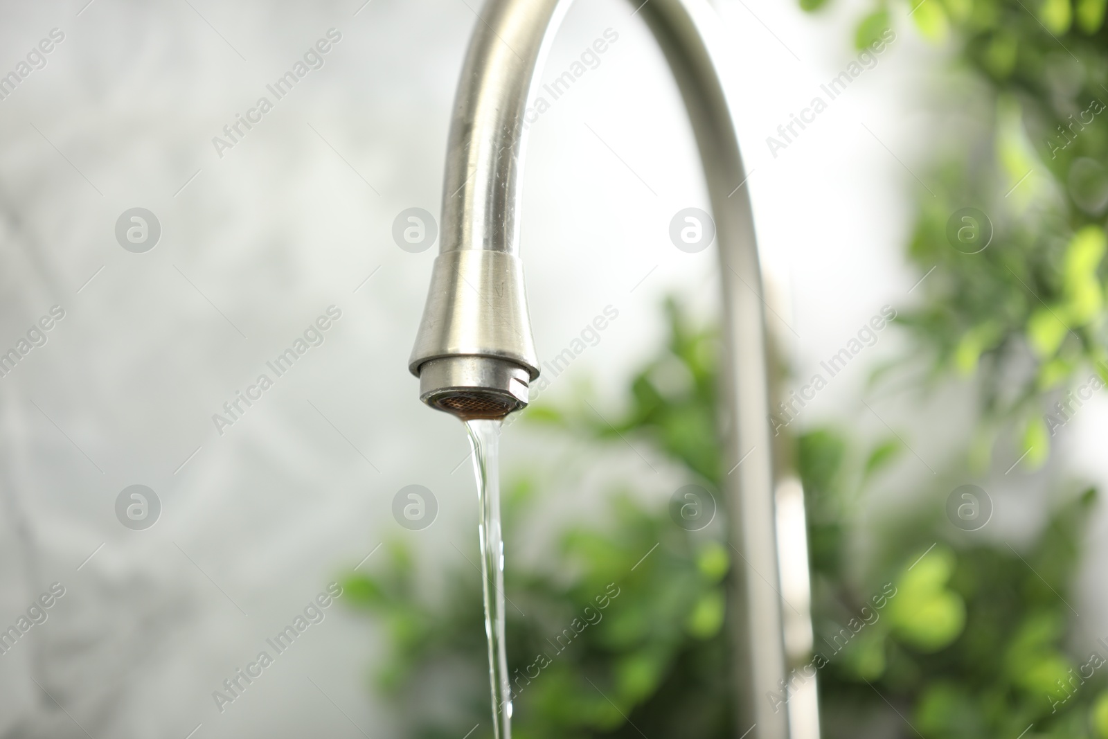 Photo of Water saving concept. Stream of water flowing from tap indoors, closeup