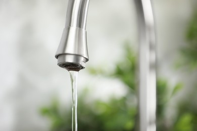 Photo of Water saving concept. Stream of water flowing from tap indoors, closeup. Space for text