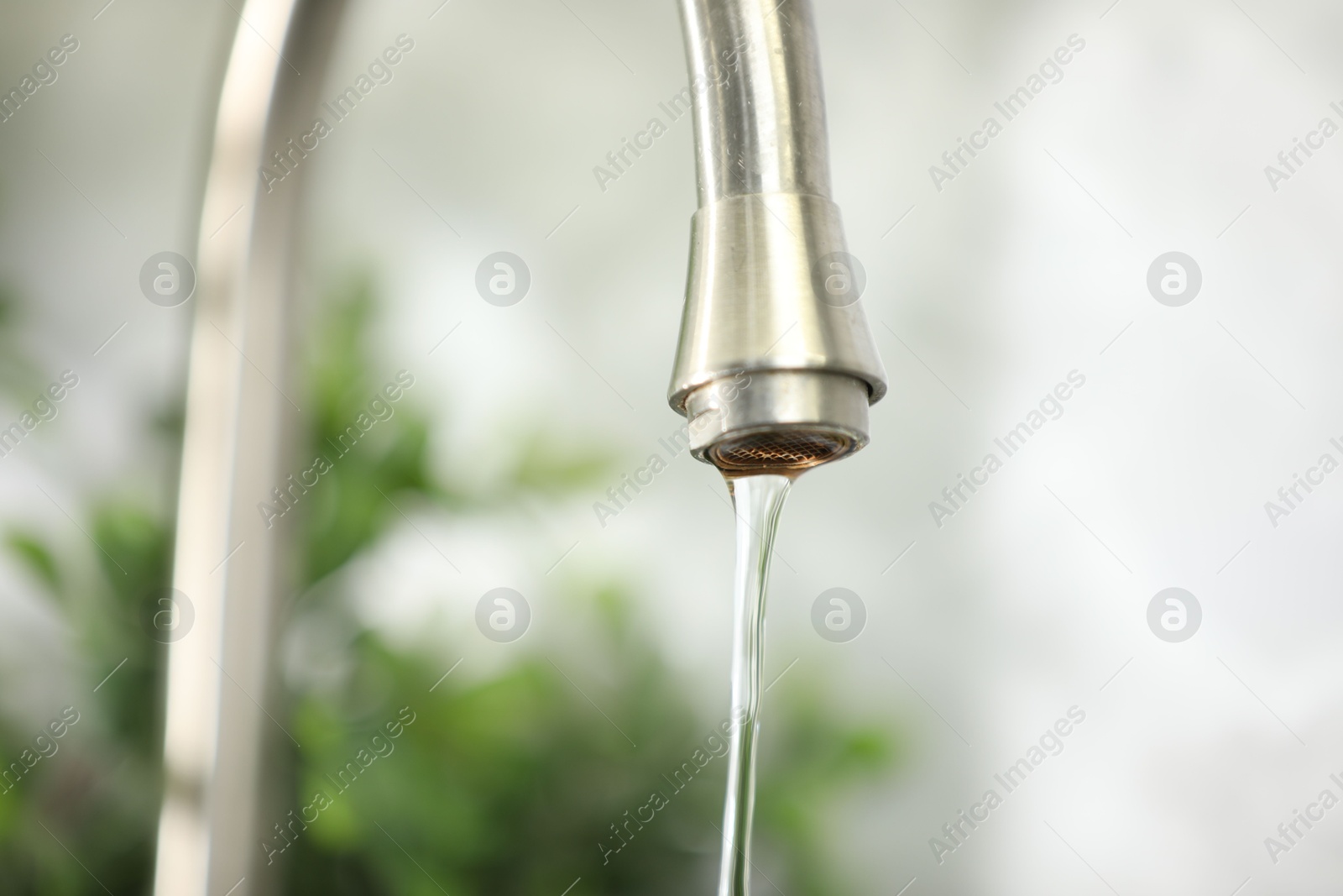 Photo of Water saving concept. Stream of water flowing from tap indoors, closeup