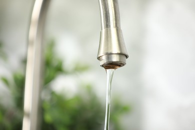 Photo of Water saving concept. Stream of water flowing from tap indoors, closeup